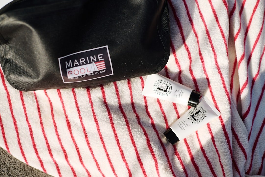 Cosmetic products and bag resting on a striped towel